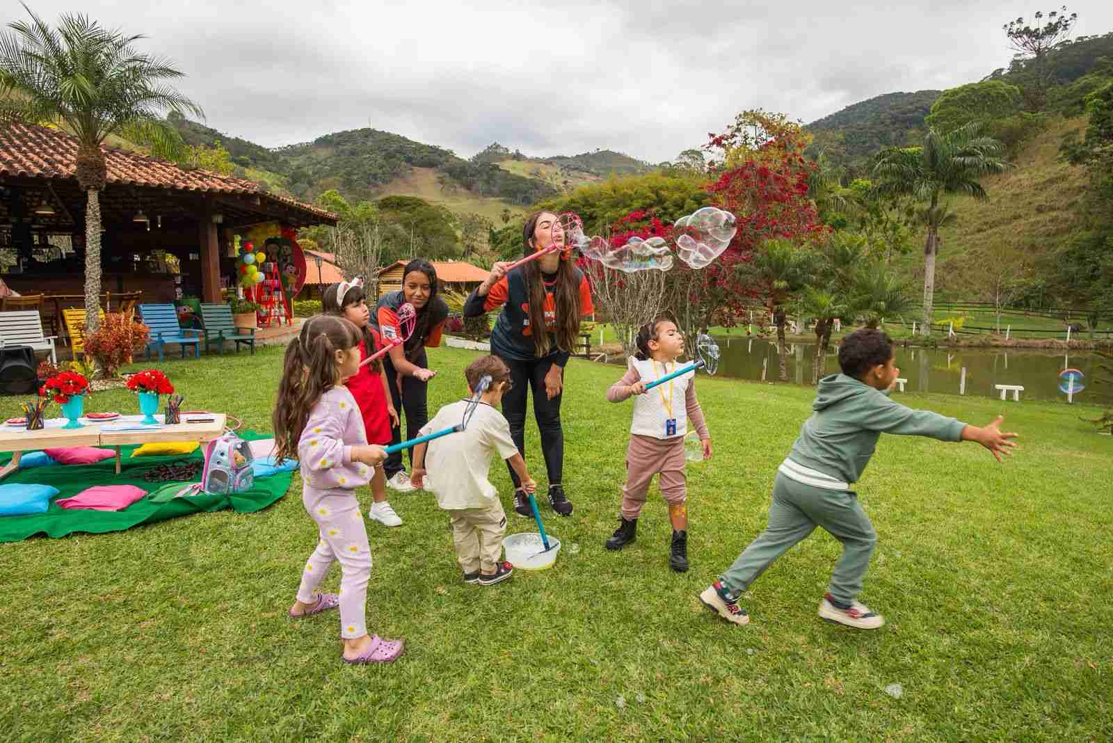 Crianças brincando com bolhas de sabão no gramado
