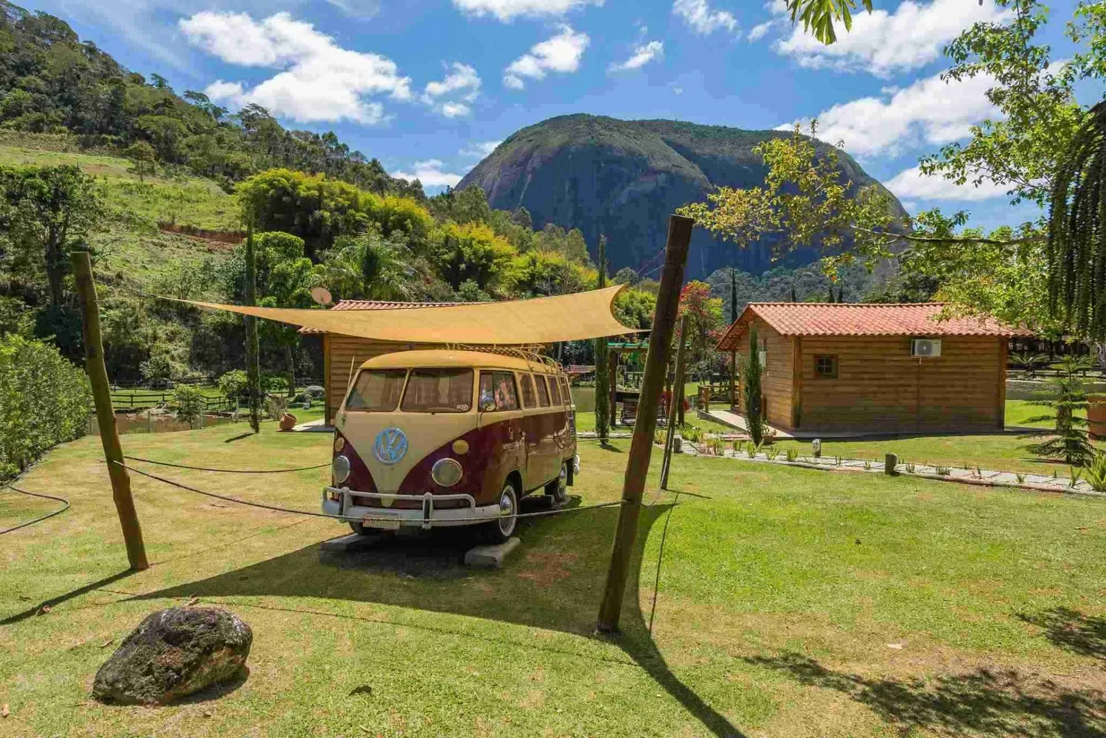 Veículo antigo exposto no gramado, com a serra ao fundo
