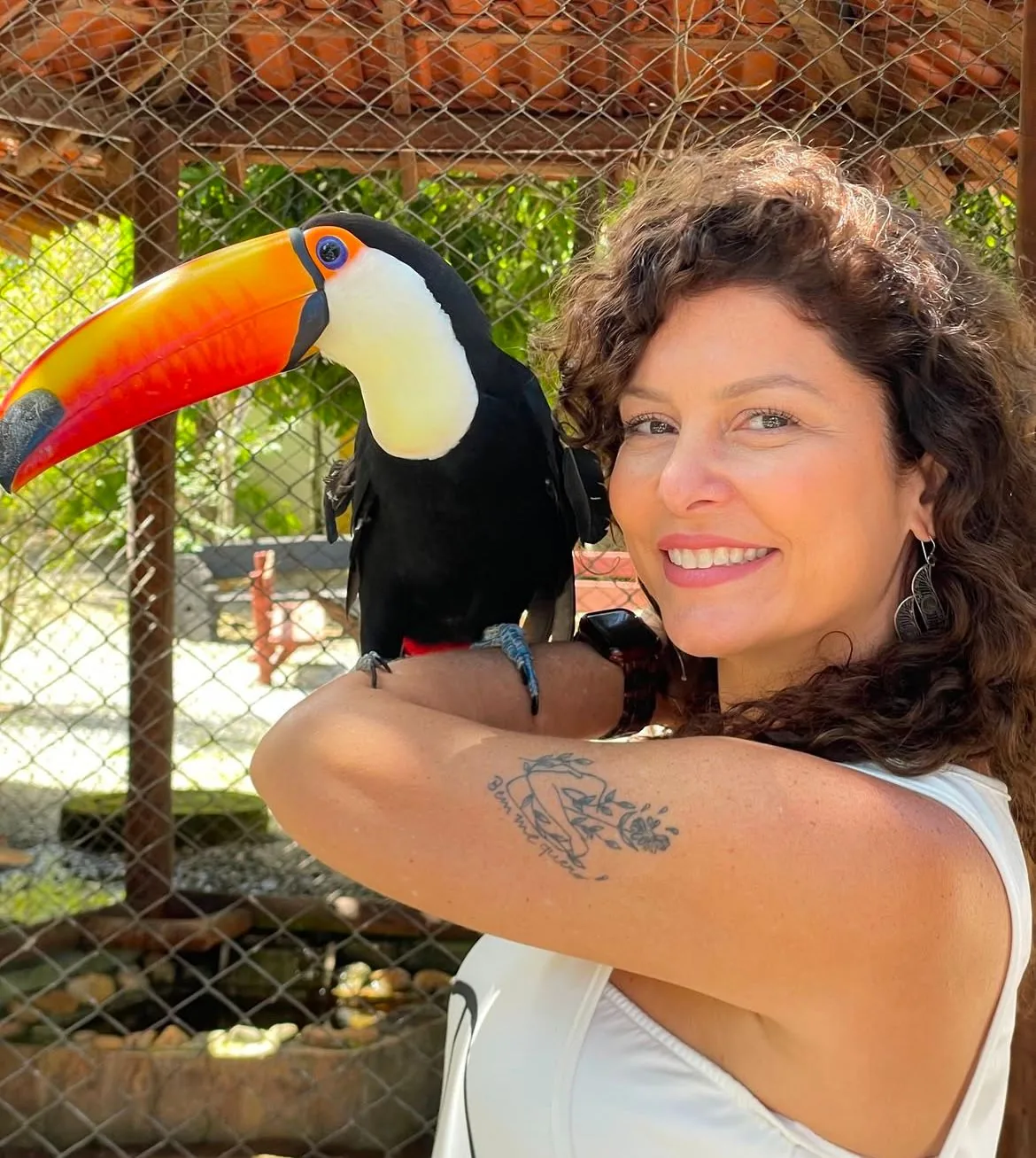 Visitante segurando um tucano próximo ao viveiro